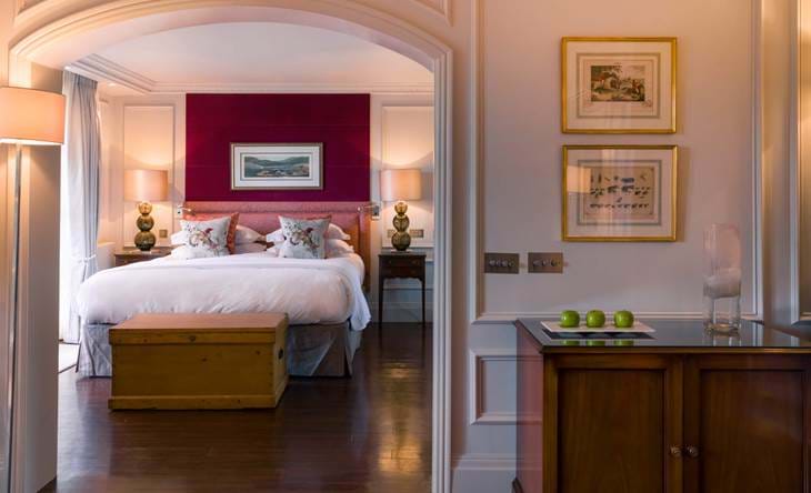 Luxurious bedroom through arched doorway with red accent wall.