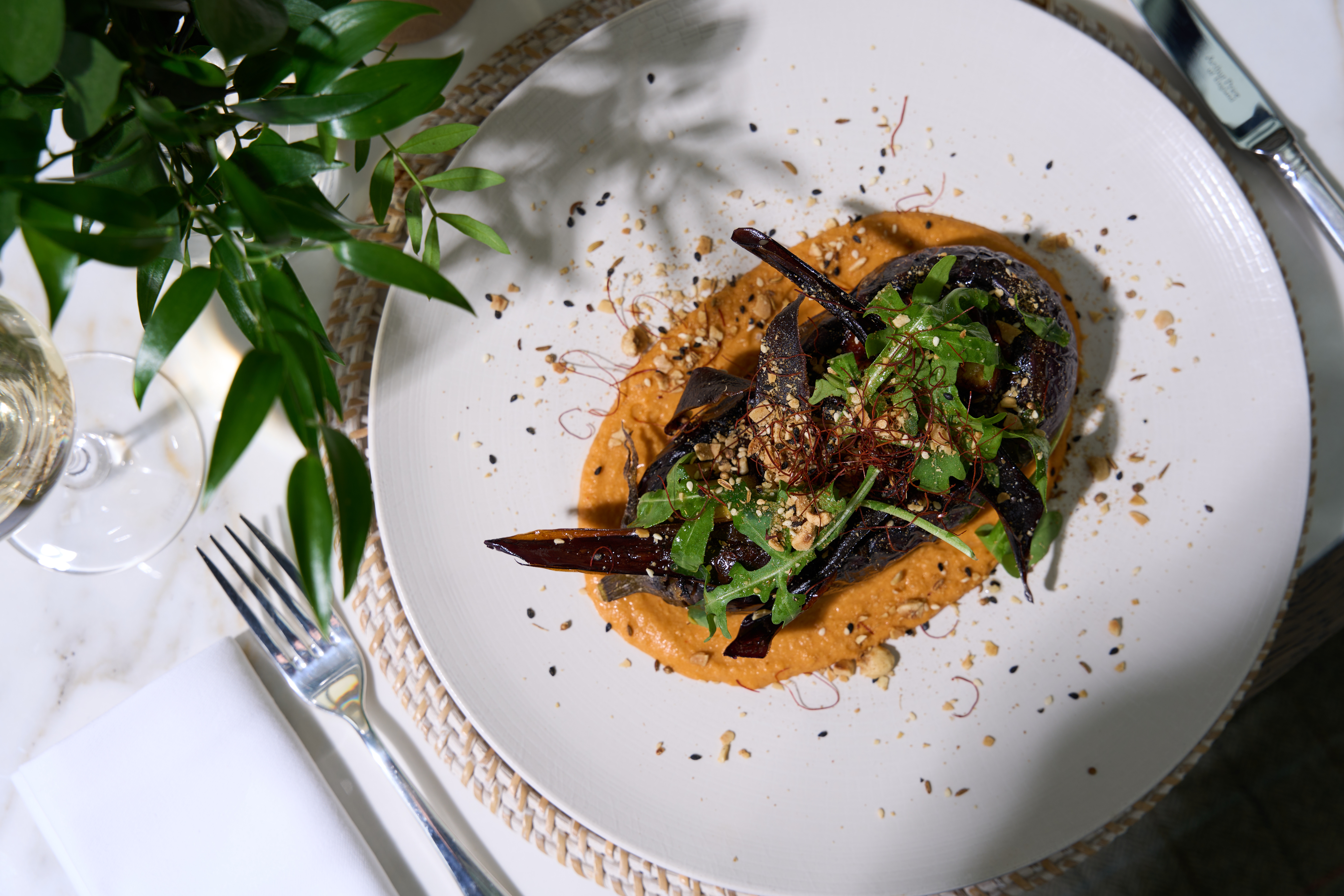 Elegant roasted vegetables on a creamy puree, topped with fresh greens and seeds.