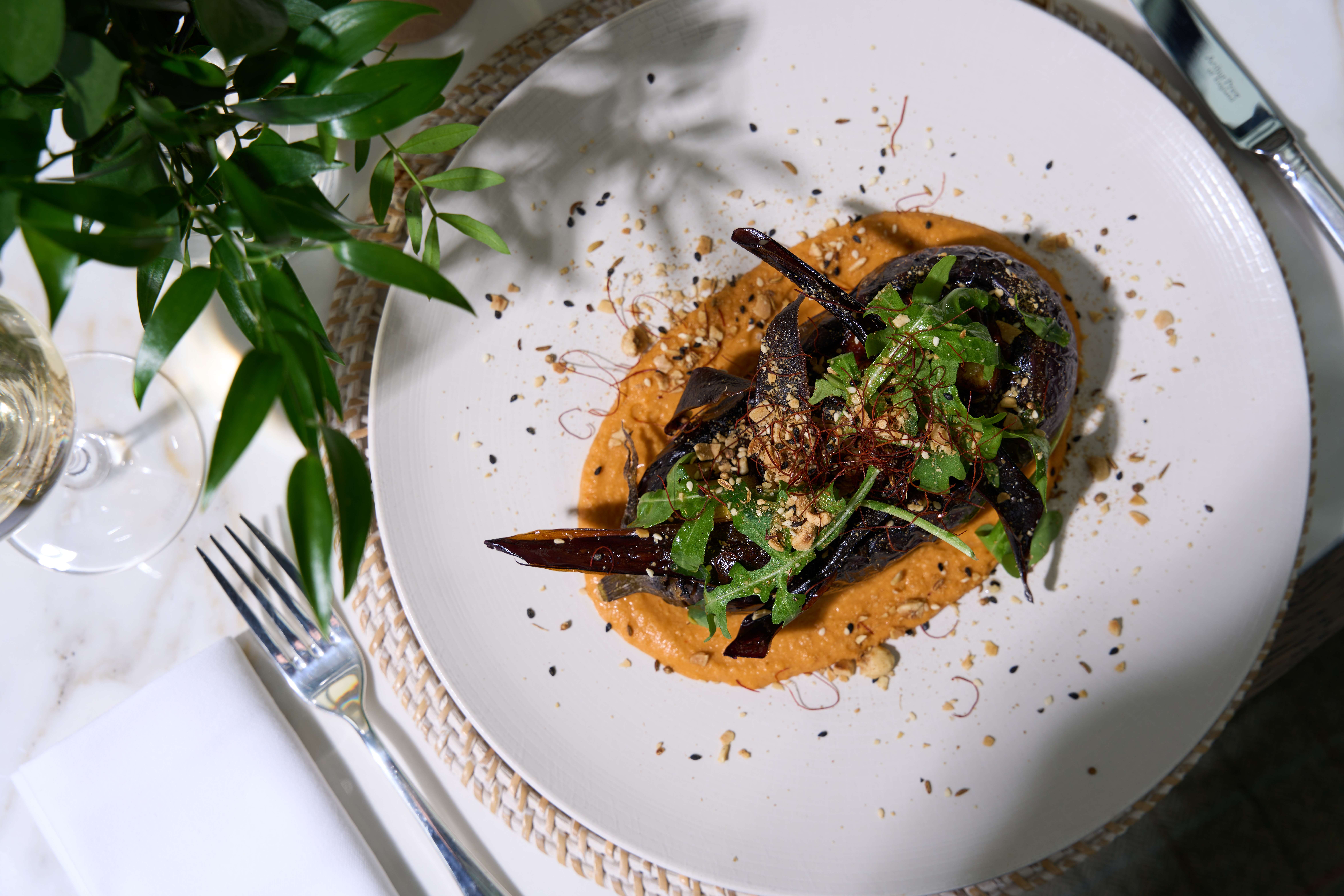 Elegant roasted vegetables on a creamy puree, topped with fresh greens and seeds.
