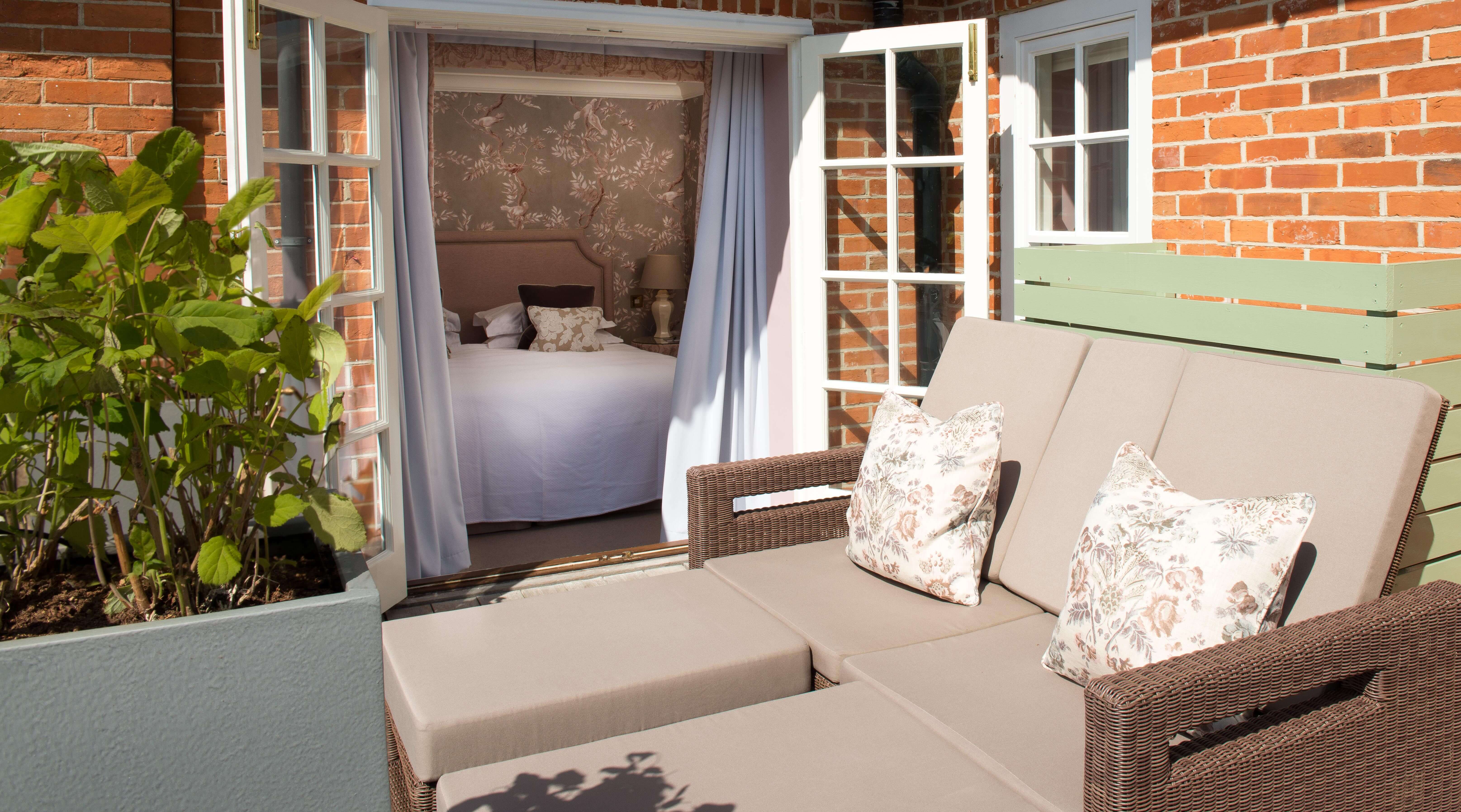 Outdoor lounge chairs leading into bedroom with floral wallpaper.