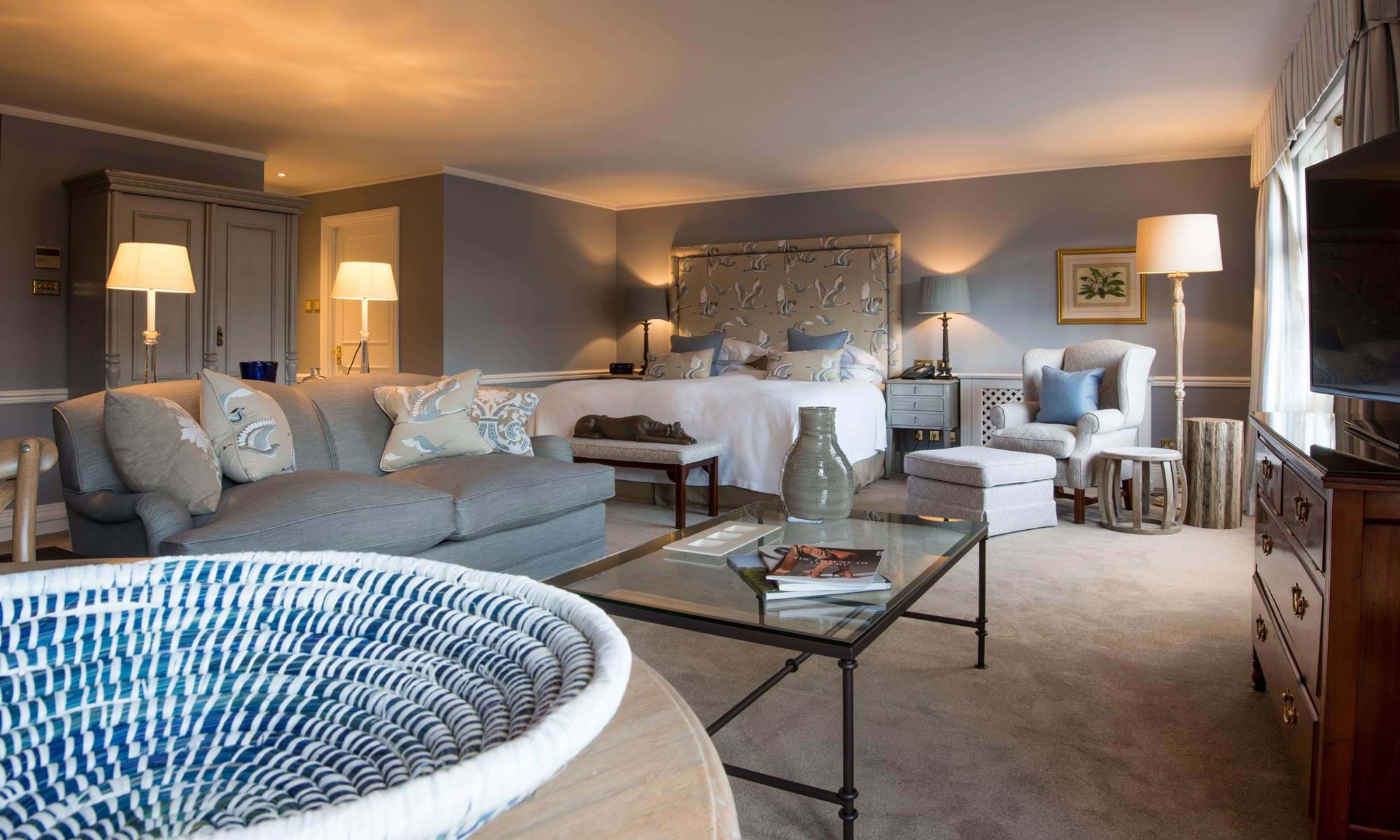 Large bedroom with grey decor and sitting area.