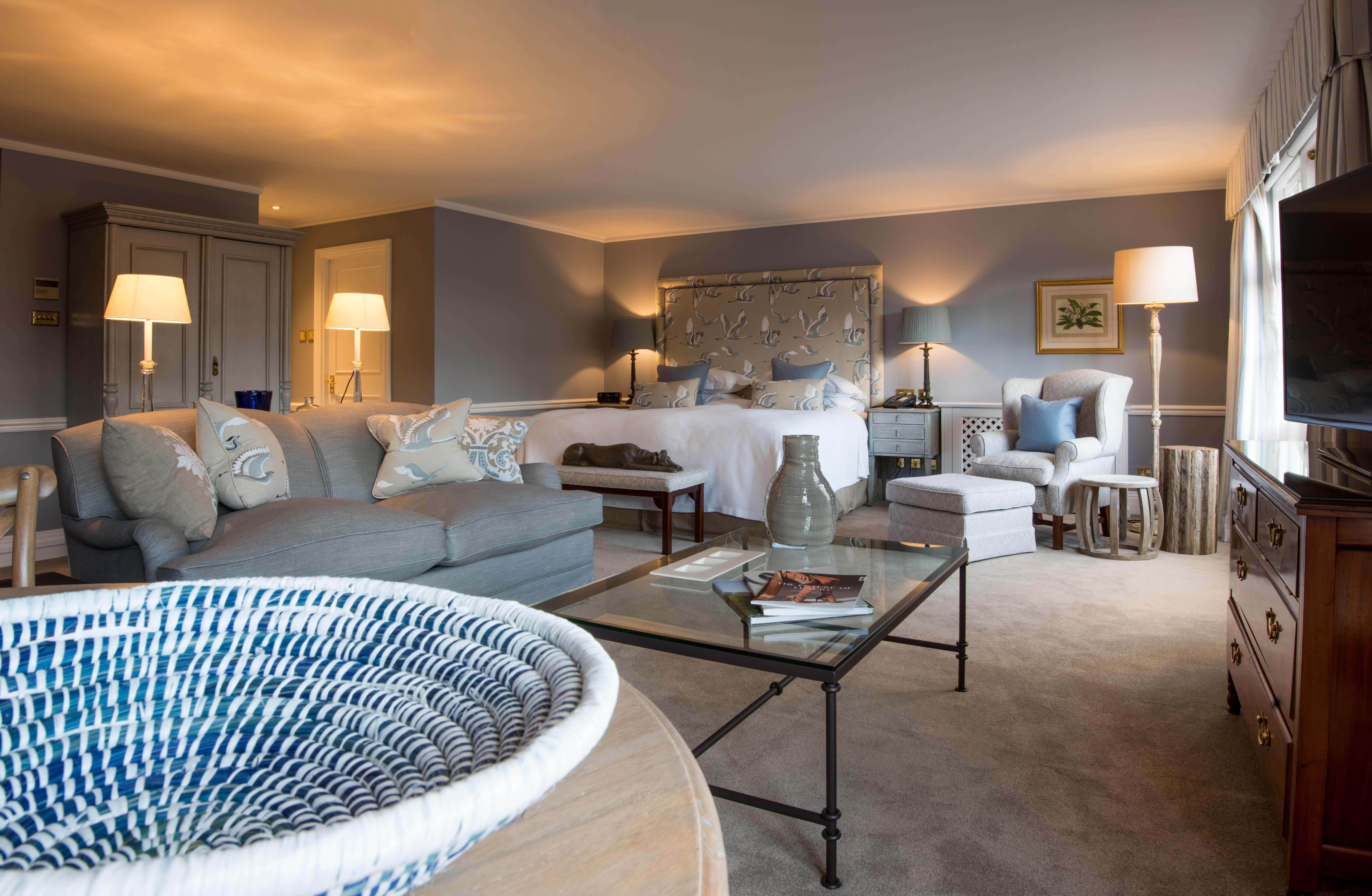 Large bedroom with grey decor and sitting area.