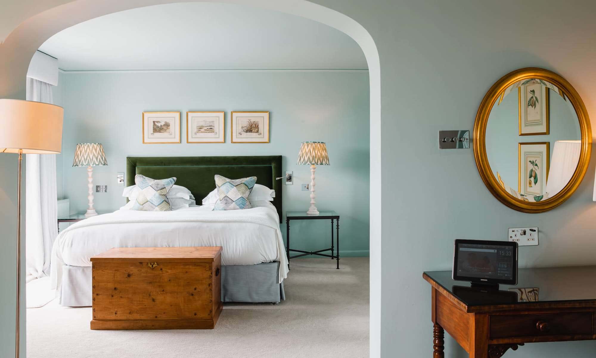 Bright bedroom with green headboard and arched entry.