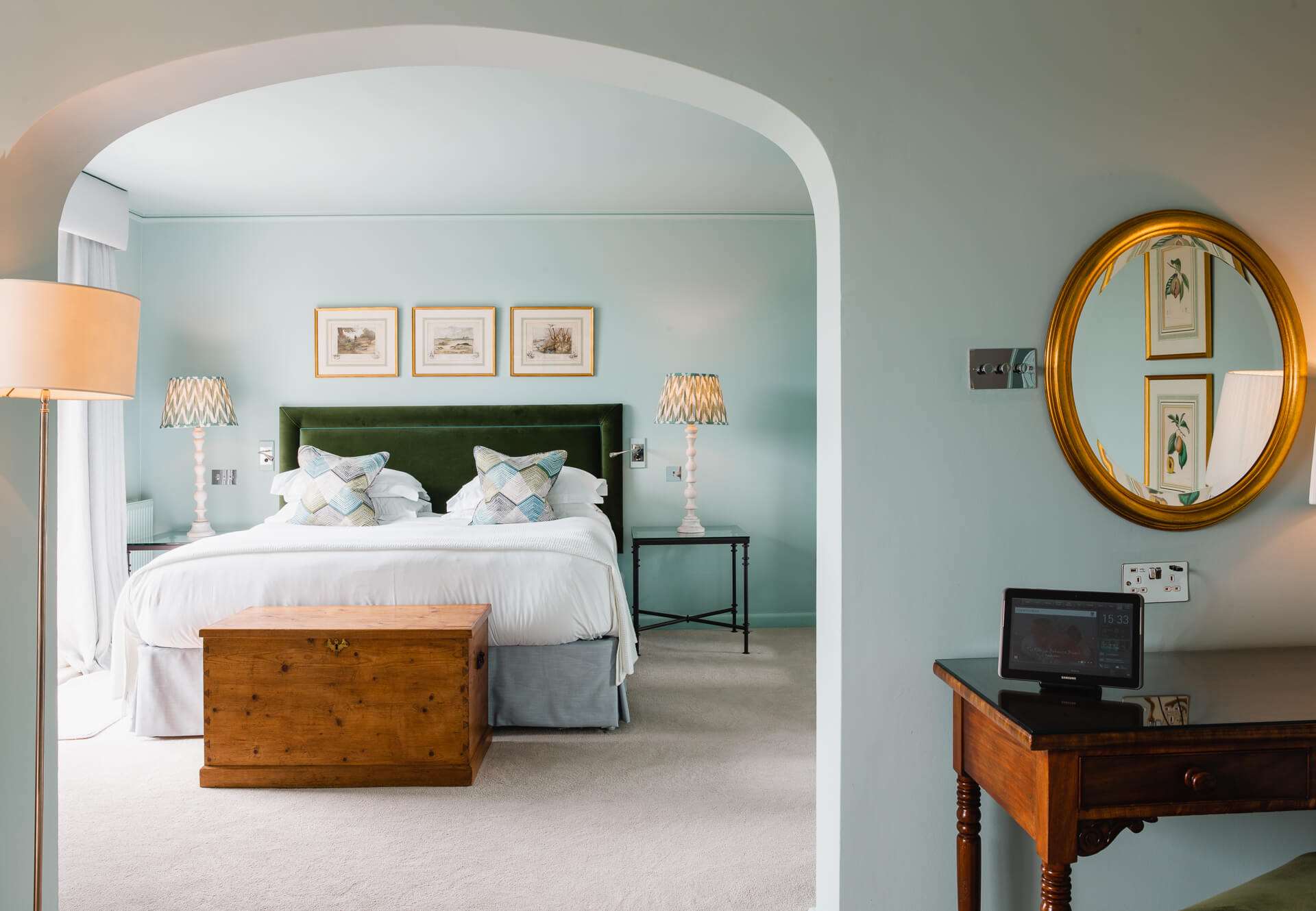 Bright bedroom with green headboard and arched entry.