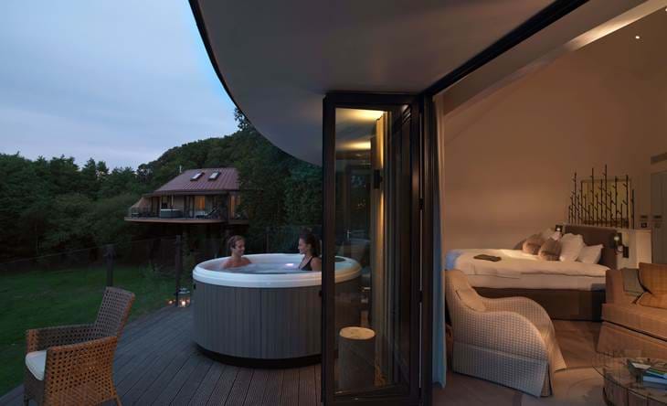 Treehouse suite with hot tub and open bedroom at dusk.