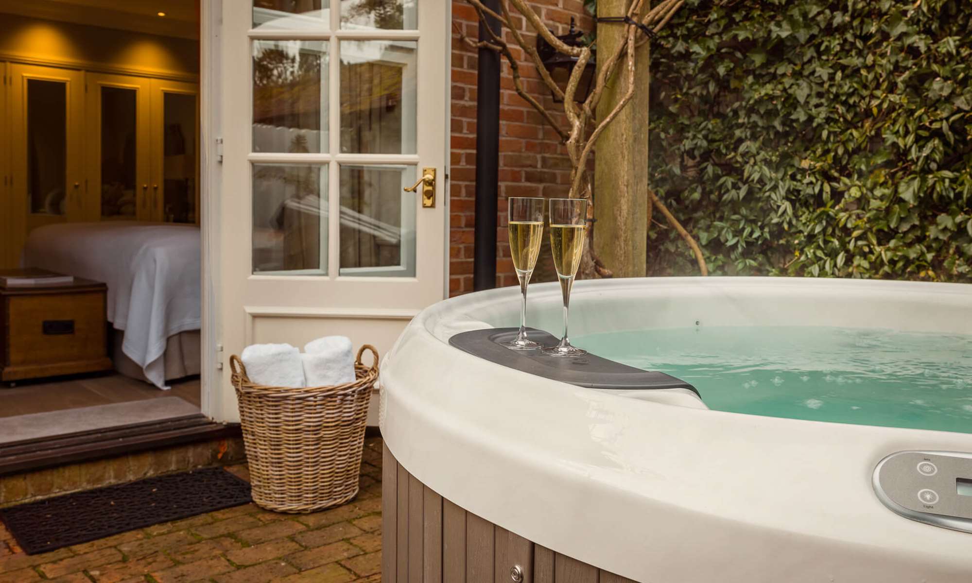 Outdoor hot tub with champagne glasses by bedroom.