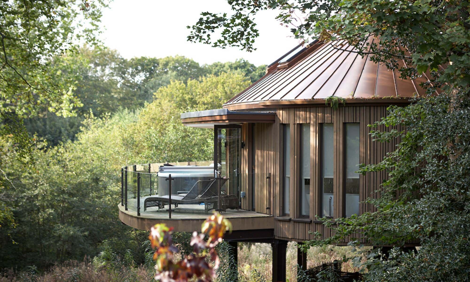 Modern treehouse with balcony surrounded by forest.