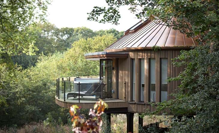 Modern treehouse with balcony surrounded by forest.